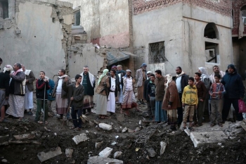 A group of Yemenis staring at some destroyed buildings