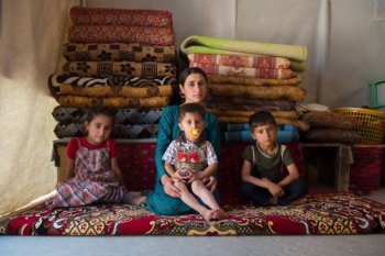 Una giovane donna yazidi siede con i suoi tre figli all&#039;interno di una tenda nel campo di Sharya, nel nord dell&#039;Iraq.