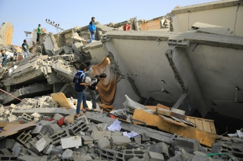 Palestinians searching between the rubble of bombed-out buildings in Gaza 
